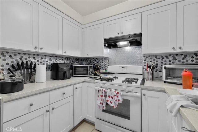 kitchen with decorative backsplash, white cabinetry, white gas stove, and light stone countertops