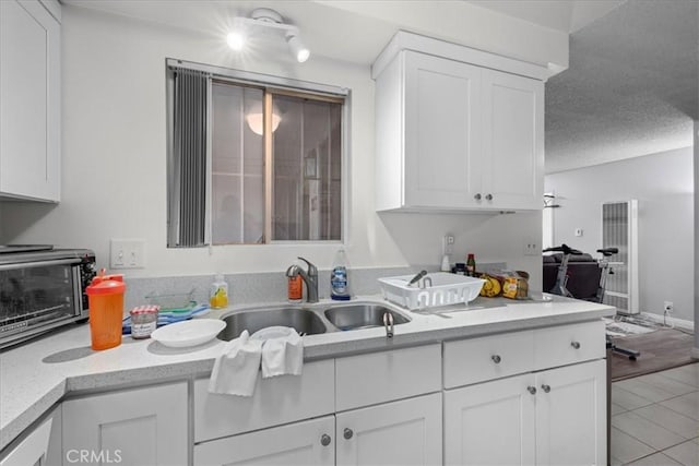 kitchen featuring white cabinets, light tile patterned floors, and sink