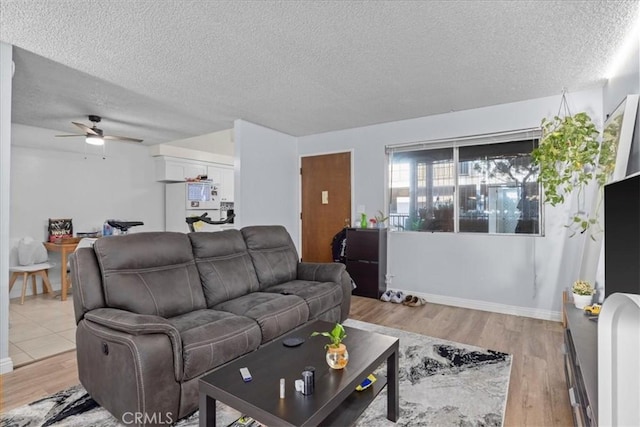 living room with ceiling fan, light hardwood / wood-style floors, and a textured ceiling