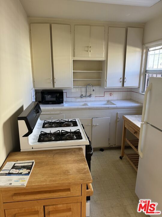 kitchen featuring white cabinets, white appliances, sink, and tasteful backsplash