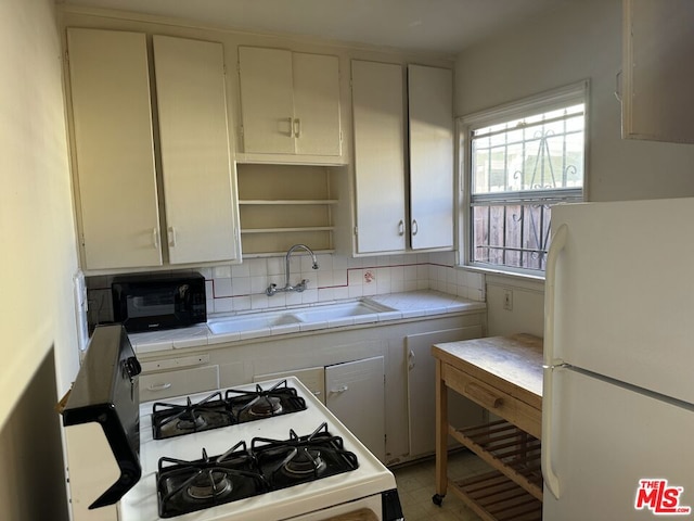 kitchen with white cabinetry, tile counters, sink, backsplash, and white appliances