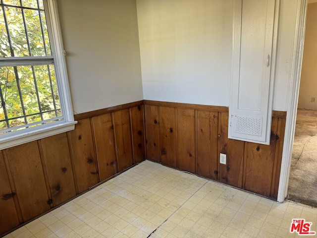 unfurnished room featuring wooden walls