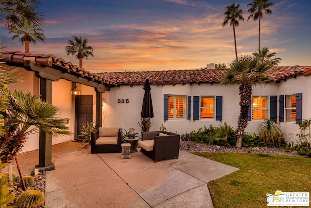 back house at dusk featuring a patio area and an outdoor hangout area