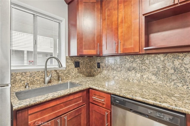 kitchen featuring stainless steel appliances, light stone counters, tasteful backsplash, and sink