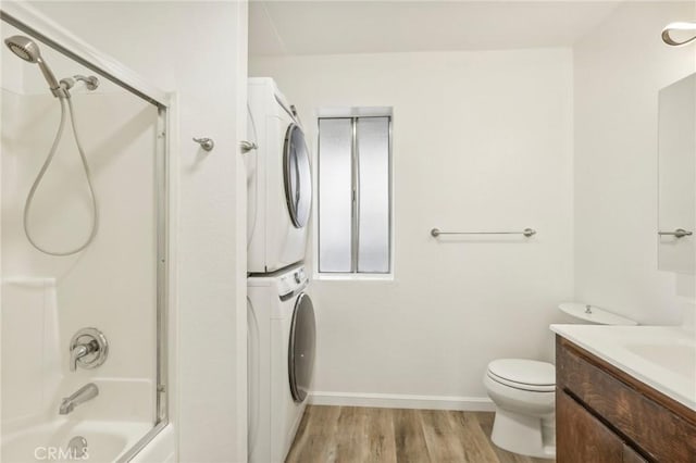 full bathroom featuring toilet, shower / bath combination, stacked washer / drying machine, wood-type flooring, and vanity