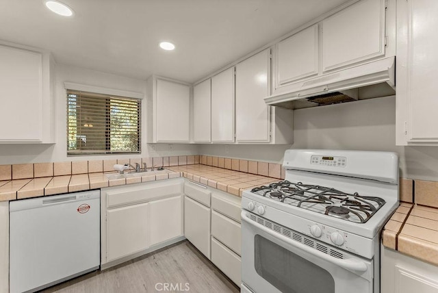 kitchen with tile counters, white cabinetry, white appliances, and light hardwood / wood-style flooring