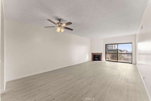 unfurnished living room featuring a tiled fireplace, light hardwood / wood-style floors, and a textured ceiling