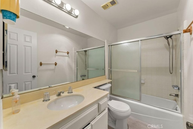 full bathroom featuring shower / bath combination with glass door, hardwood / wood-style flooring, vanity, and toilet