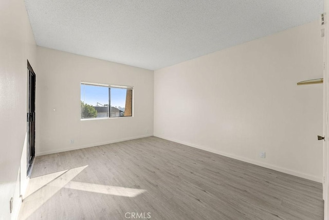 unfurnished room featuring a textured ceiling and light hardwood / wood-style flooring