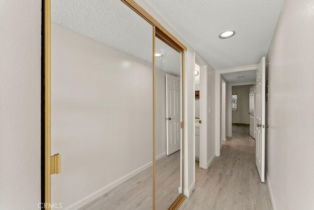 hall with light hardwood / wood-style floors and a textured ceiling