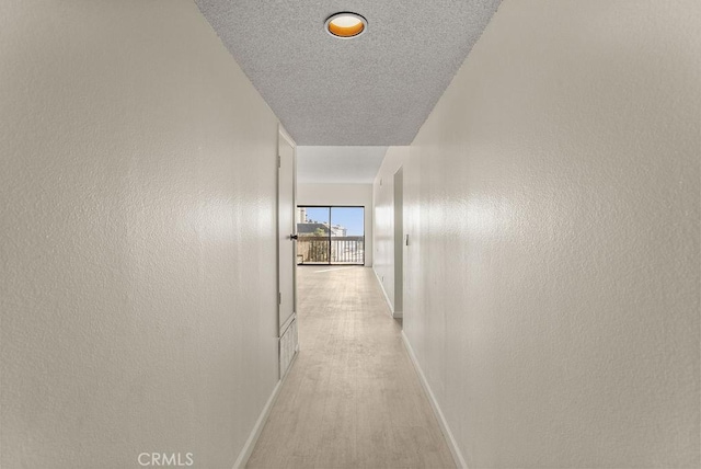 corridor with light hardwood / wood-style flooring and a textured ceiling