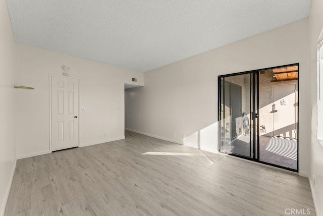 unfurnished room featuring a textured ceiling and light hardwood / wood-style flooring