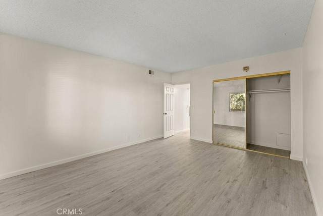 unfurnished bedroom with a textured ceiling, light hardwood / wood-style flooring, and a closet