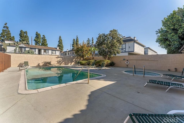 view of swimming pool featuring a patio and a hot tub