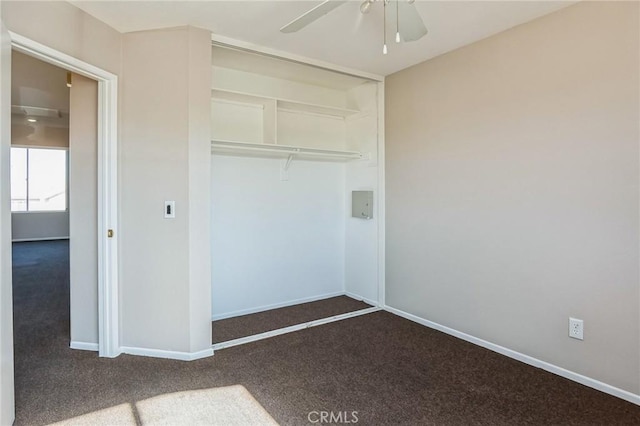 unfurnished bedroom with dark colored carpet, a closet, and ceiling fan