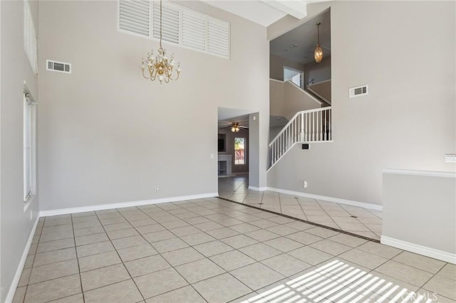 unfurnished living room with beam ceiling, ceiling fan with notable chandelier, light tile patterned flooring, and a high ceiling