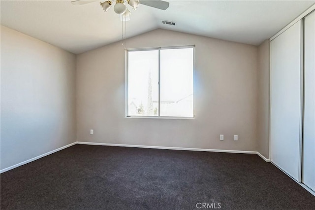 spare room featuring dark colored carpet, ceiling fan, and vaulted ceiling