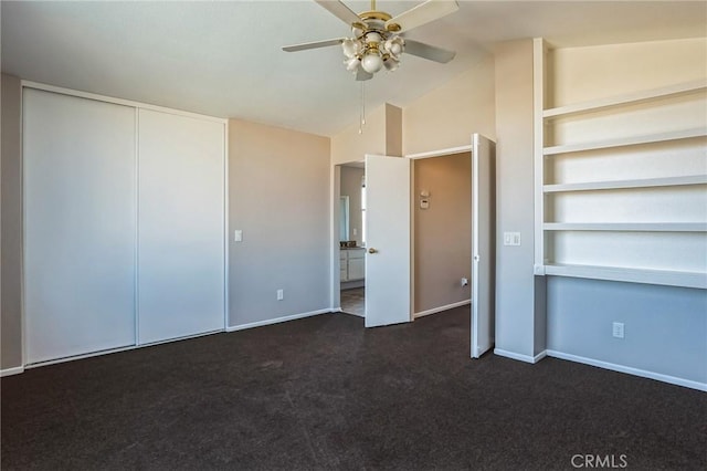 interior space featuring ceiling fan, dark carpet, and vaulted ceiling