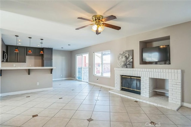 unfurnished living room featuring ceiling fan, light tile patterned flooring, and a brick fireplace