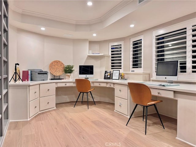 office with built in desk, light hardwood / wood-style floors, ornamental molding, and a raised ceiling