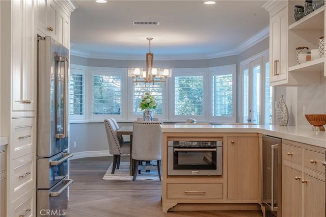 kitchen with pendant lighting, beverage cooler, stainless steel appliances, a chandelier, and crown molding