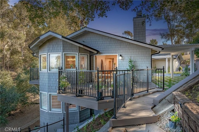 back house at dusk featuring a wooden deck