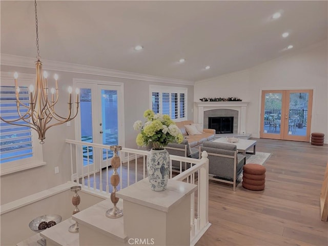 living room featuring an inviting chandelier, crown molding, light hardwood / wood-style floors, and french doors