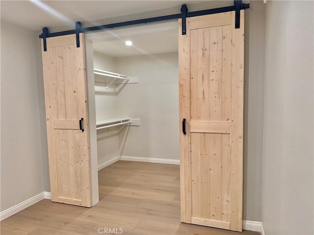 walk in closet featuring a barn door and light wood-type flooring