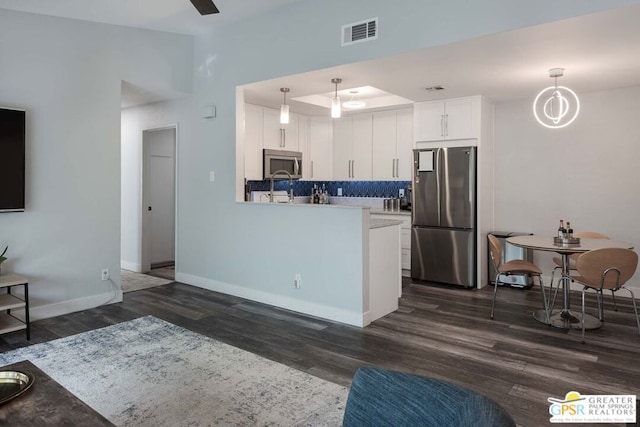 kitchen with decorative light fixtures, dark hardwood / wood-style flooring, stainless steel appliances, and white cabinetry