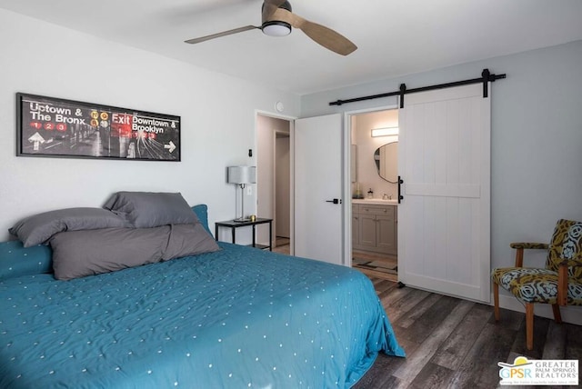 bedroom with ceiling fan, a barn door, dark hardwood / wood-style flooring, and ensuite bath