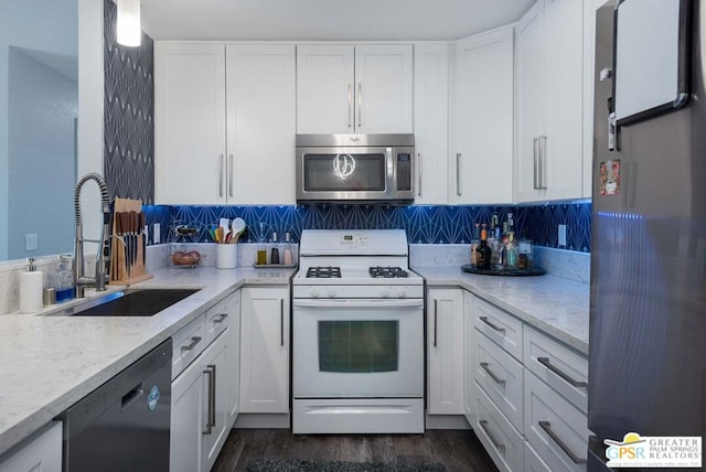 kitchen featuring white cabinets, sink, light stone countertops, appliances with stainless steel finishes, and dark hardwood / wood-style flooring