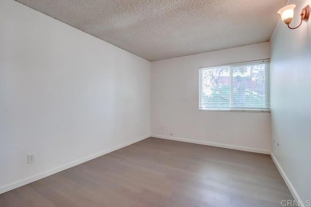 empty room featuring wood-type flooring and a textured ceiling