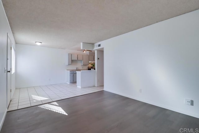 unfurnished living room featuring sink, a textured ceiling, and light hardwood / wood-style floors