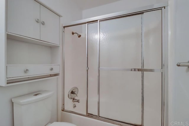 bathroom featuring toilet and combined bath / shower with glass door