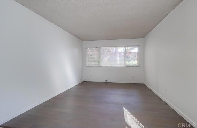 empty room with dark wood-type flooring and a textured ceiling