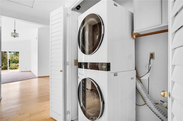 clothes washing area featuring light wood-type flooring and stacked washing maching and dryer