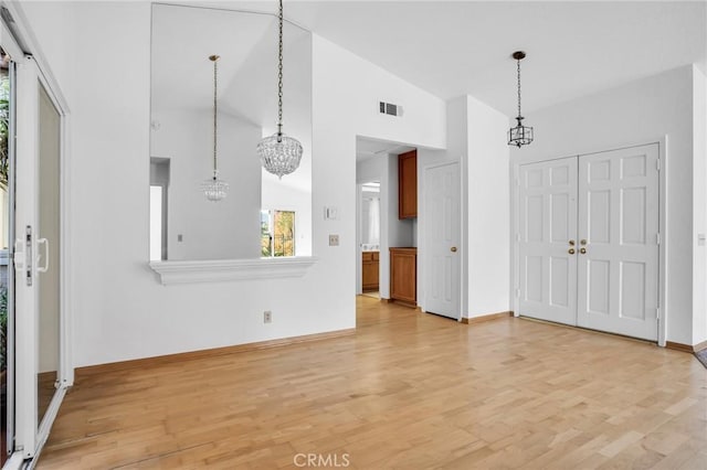 interior space with a notable chandelier, light hardwood / wood-style floors, and high vaulted ceiling