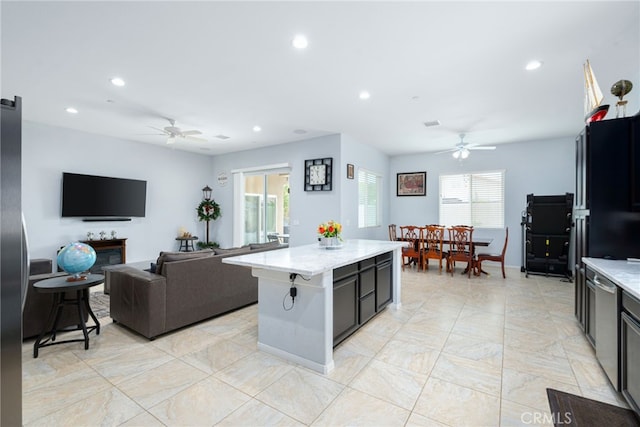 kitchen featuring a kitchen island, ceiling fan, and a healthy amount of sunlight