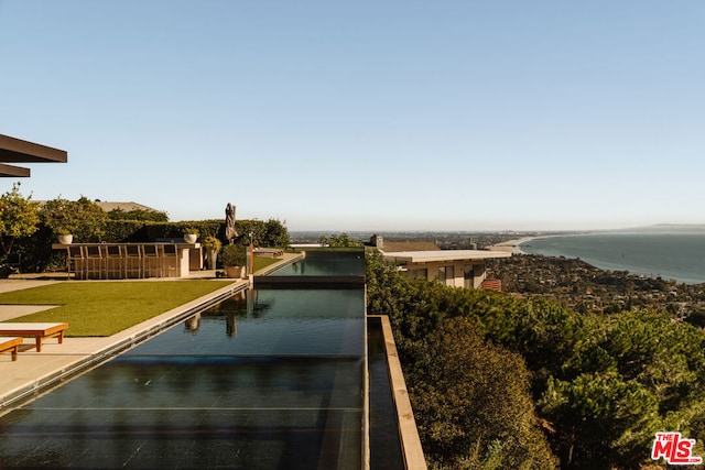 view of pool with a yard and a water view