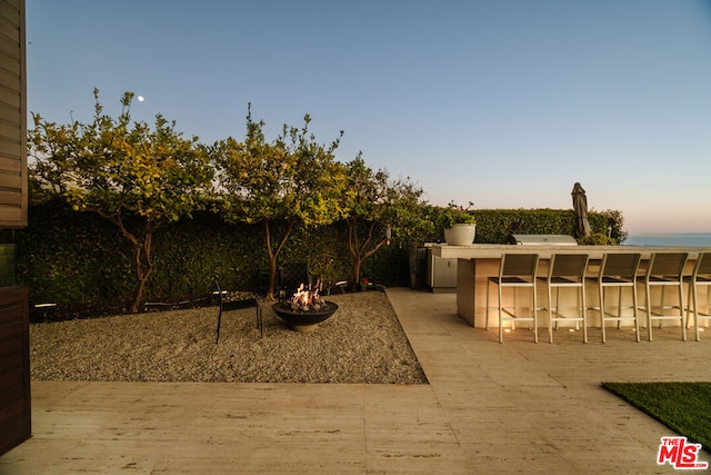 patio terrace at dusk with an outdoor bar and a fire pit