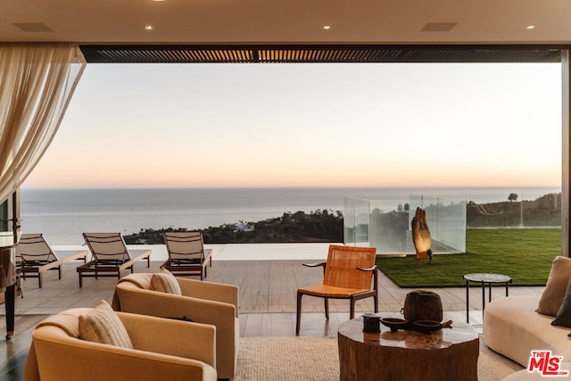 patio terrace at dusk featuring an outdoor hangout area and a water view