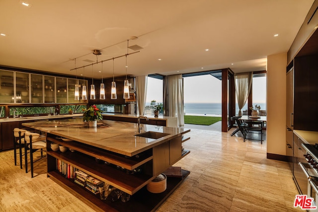 bar featuring stainless steel range, a water view, hanging light fixtures, and sink