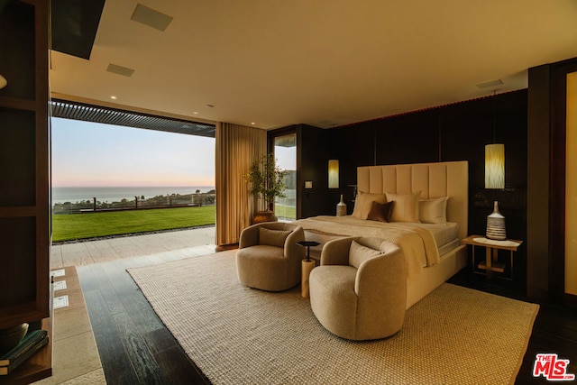 bedroom featuring hardwood / wood-style floors, a wall of windows, and golf simulator