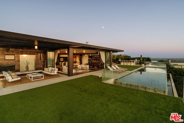 back house at dusk featuring a yard, an outdoor hangout area, and a patio