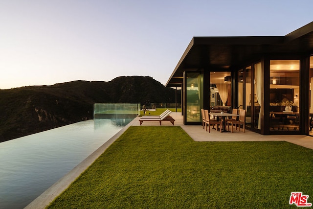 yard at dusk featuring a mountain view and a patio