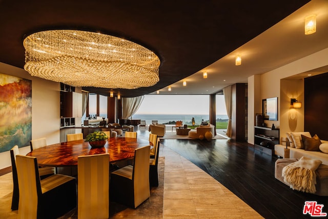 dining room featuring hardwood / wood-style floors, a water view, a wall of windows, and a chandelier