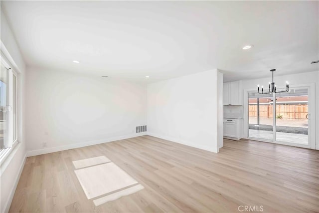 empty room with light wood-type flooring and a chandelier