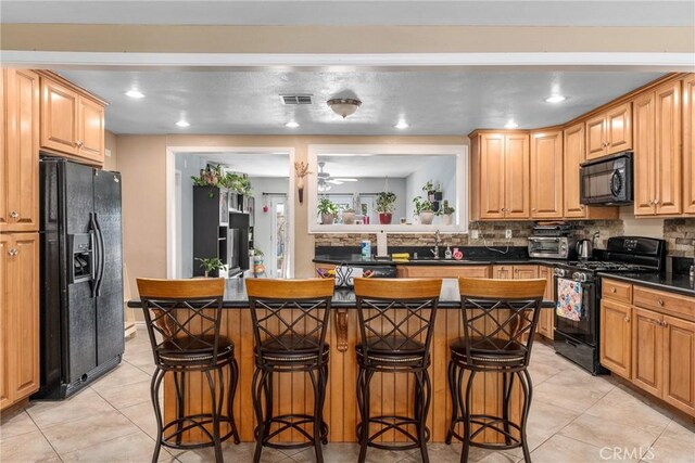 kitchen featuring a breakfast bar, decorative backsplash, ceiling fan, and black appliances