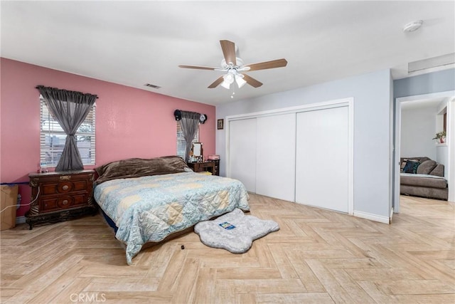 bedroom with ceiling fan, a closet, and light parquet flooring