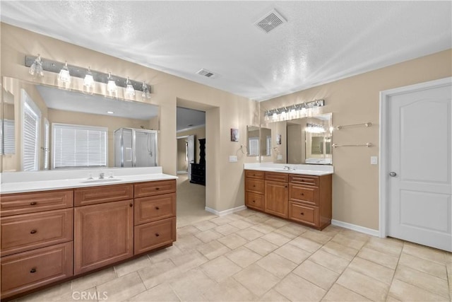 bathroom with tile patterned flooring, a textured ceiling, vanity, and a shower with door